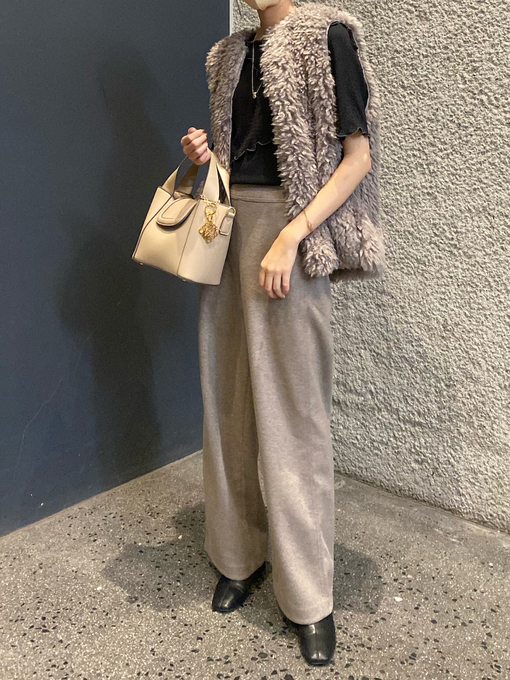 ブラウン系のベスト、ブラック系のブーツ、ベージュ系のショルダーバッグを着用したレディースの秋コーディネートの3枚目の写真