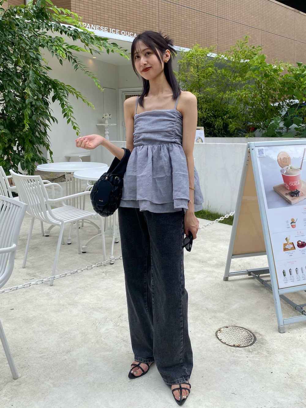 グレー系のキャミソール、ブラック系のショルダーバッグ、グレー系のデニムパンツを着用したレディースの夏コーディネートの2枚目の写真