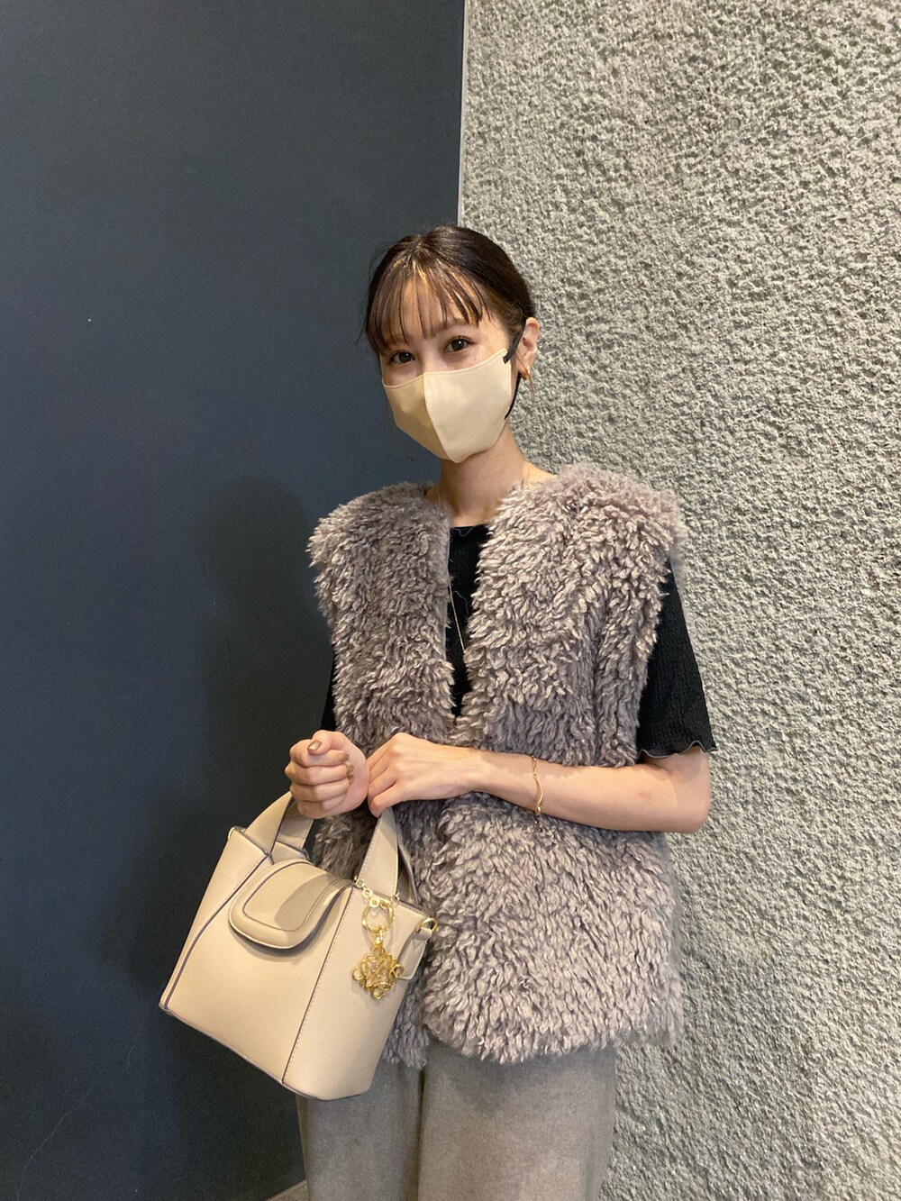 ブラウン系のベスト、ブラック系のブーツ、ベージュ系のショルダーバッグを着用したレディースの秋コーディネートの2枚目の写真