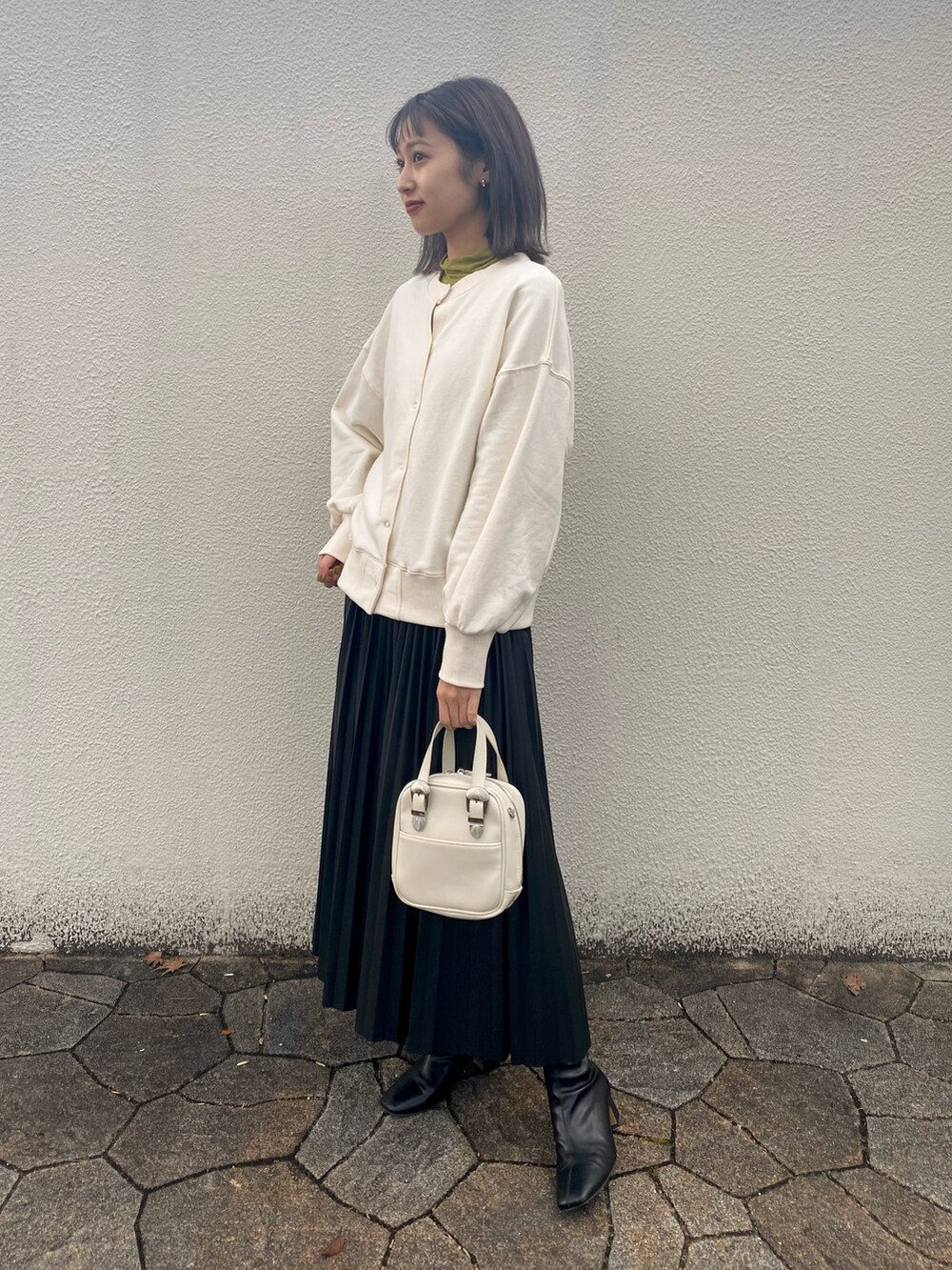 ホワイト系のショルダーバッグ、ブラック系のブーツ、グリーン系のTシャツ/カットソーを着用したレディースの冬コーディネートの2枚目の写真