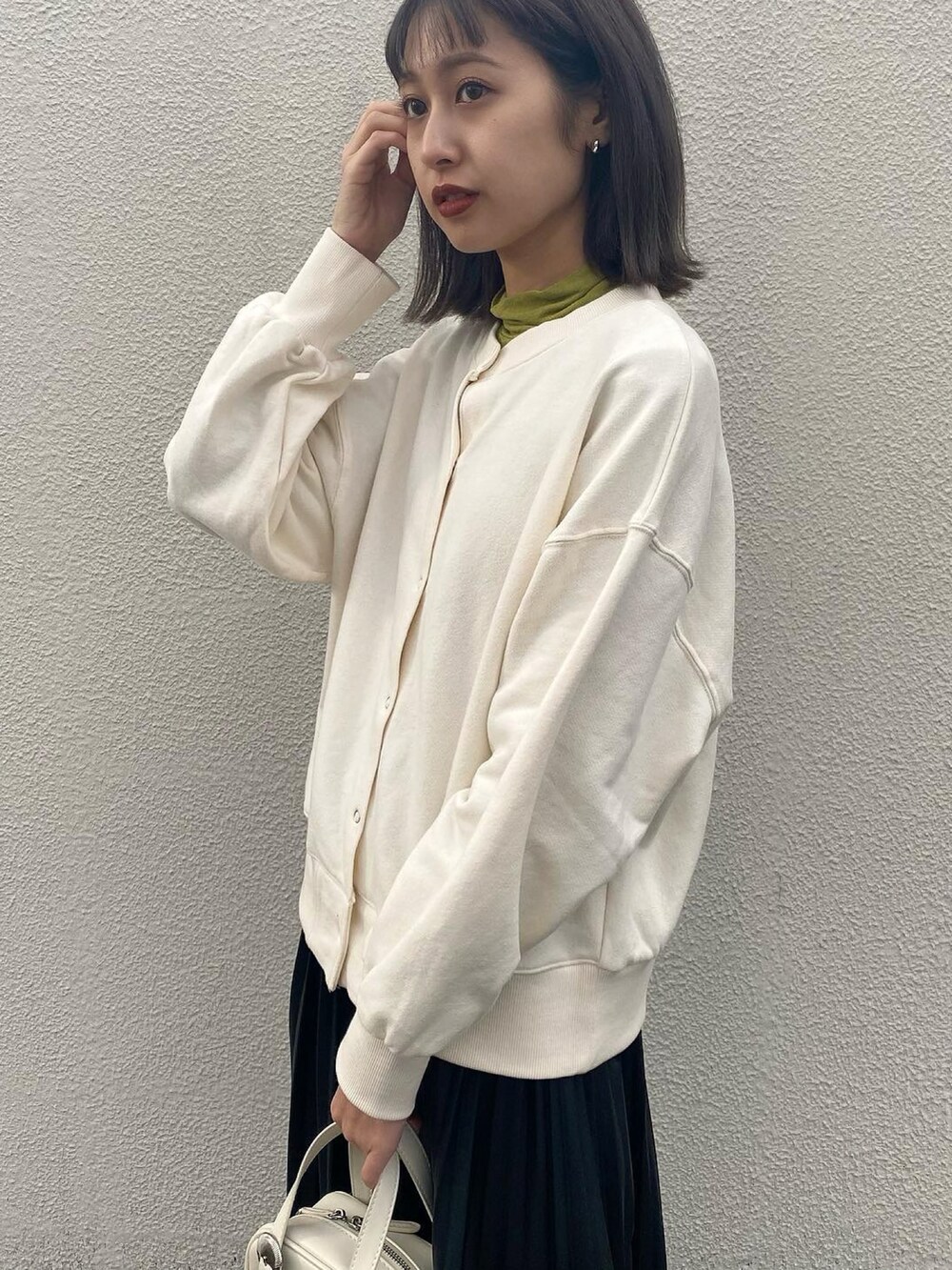 ホワイト系のショルダーバッグ、ブラック系のブーツ、グリーン系のTシャツ/カットソーを着用したレディースの冬コーディネートの3枚目の写真