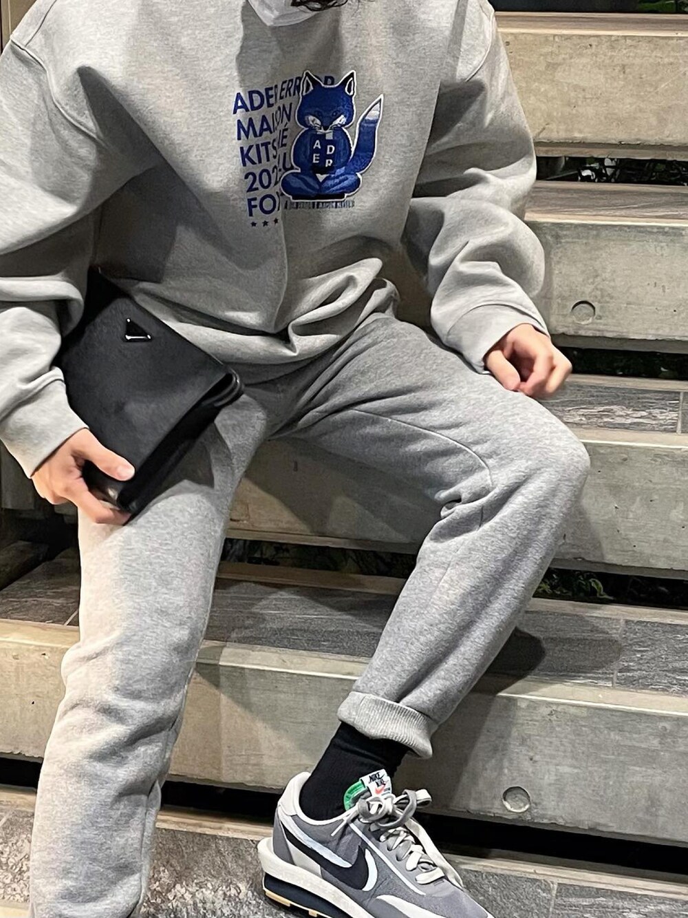 グレー系のスウェット、ブラック系のクラッチバッグ、グレー系のスニーカーを着用したメンズの秋コーディネートの2枚目の写真