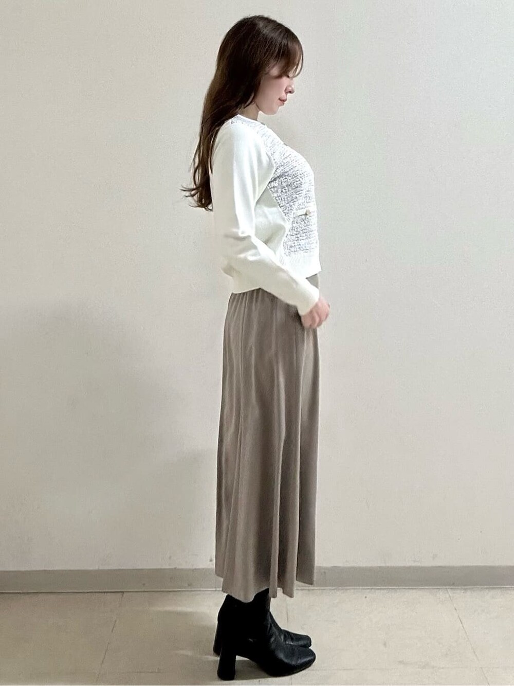 ベージュ系のトレンチコート、ホワイト系のカーディガン/ボレロ、ベージュ系のスカートを着用したレディースの冬コーディネートの6枚目の写真