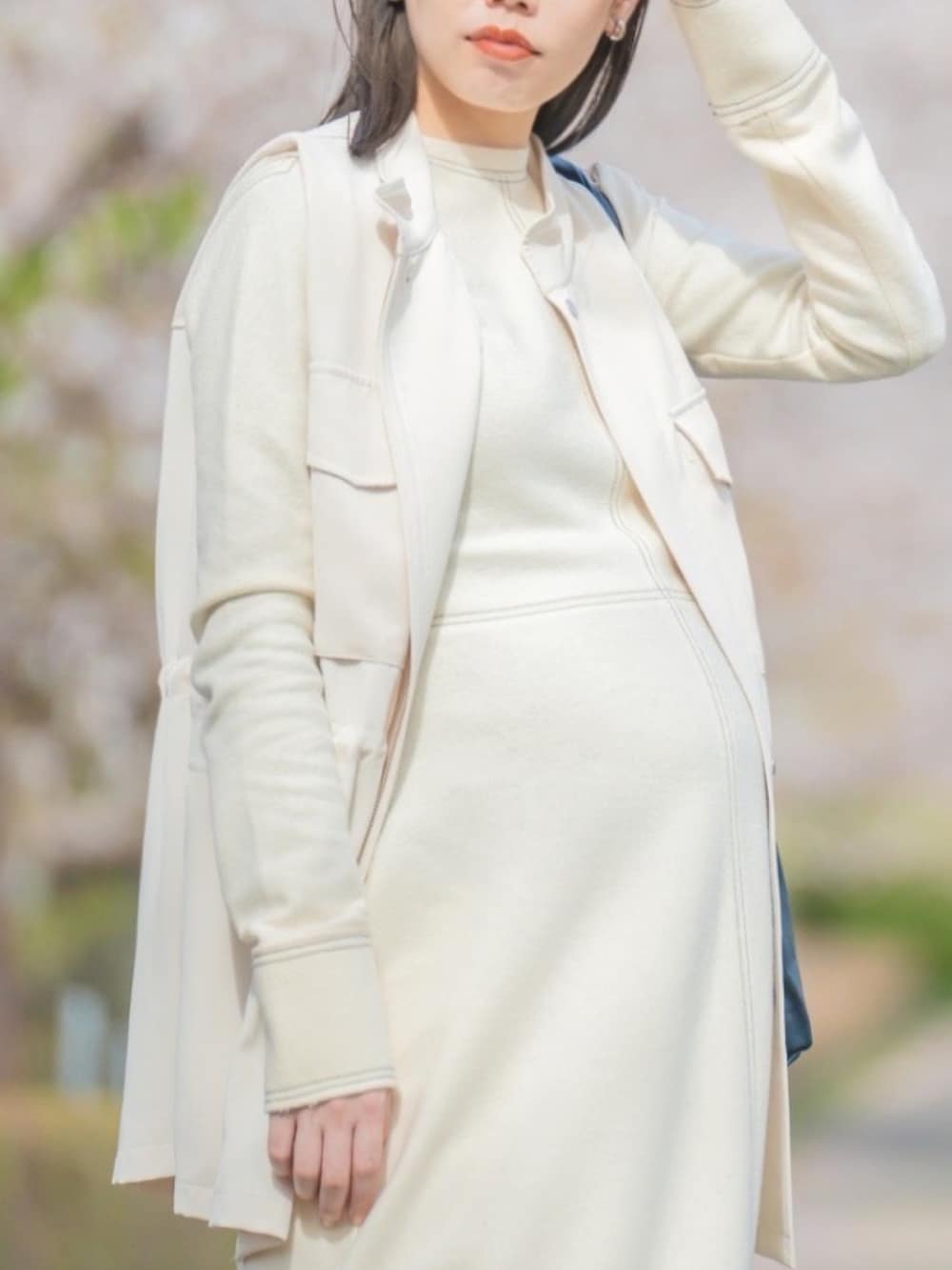 ベージュ系のスニーカー、ホワイト系のワンピース、ホワイト系のベストを着用したレディースの秋コーディネートの2枚目の写真