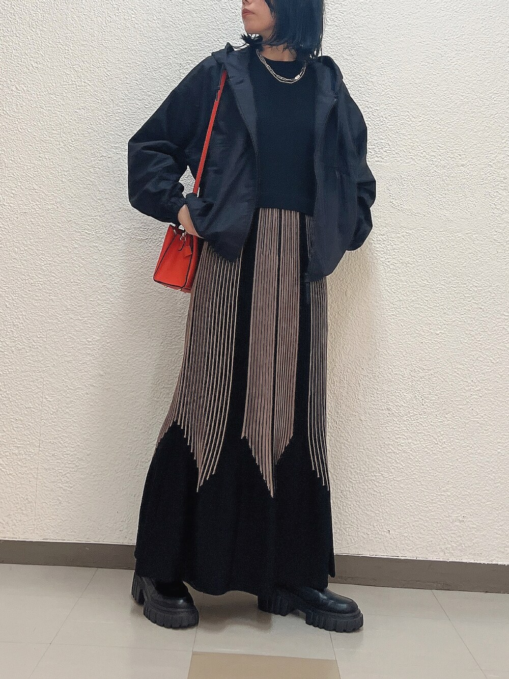 ブラック系のその他アウター、オレンジ系のバッグ、ブラック系のワンピースを着用したレディースの冬コーディネートの2枚目の写真