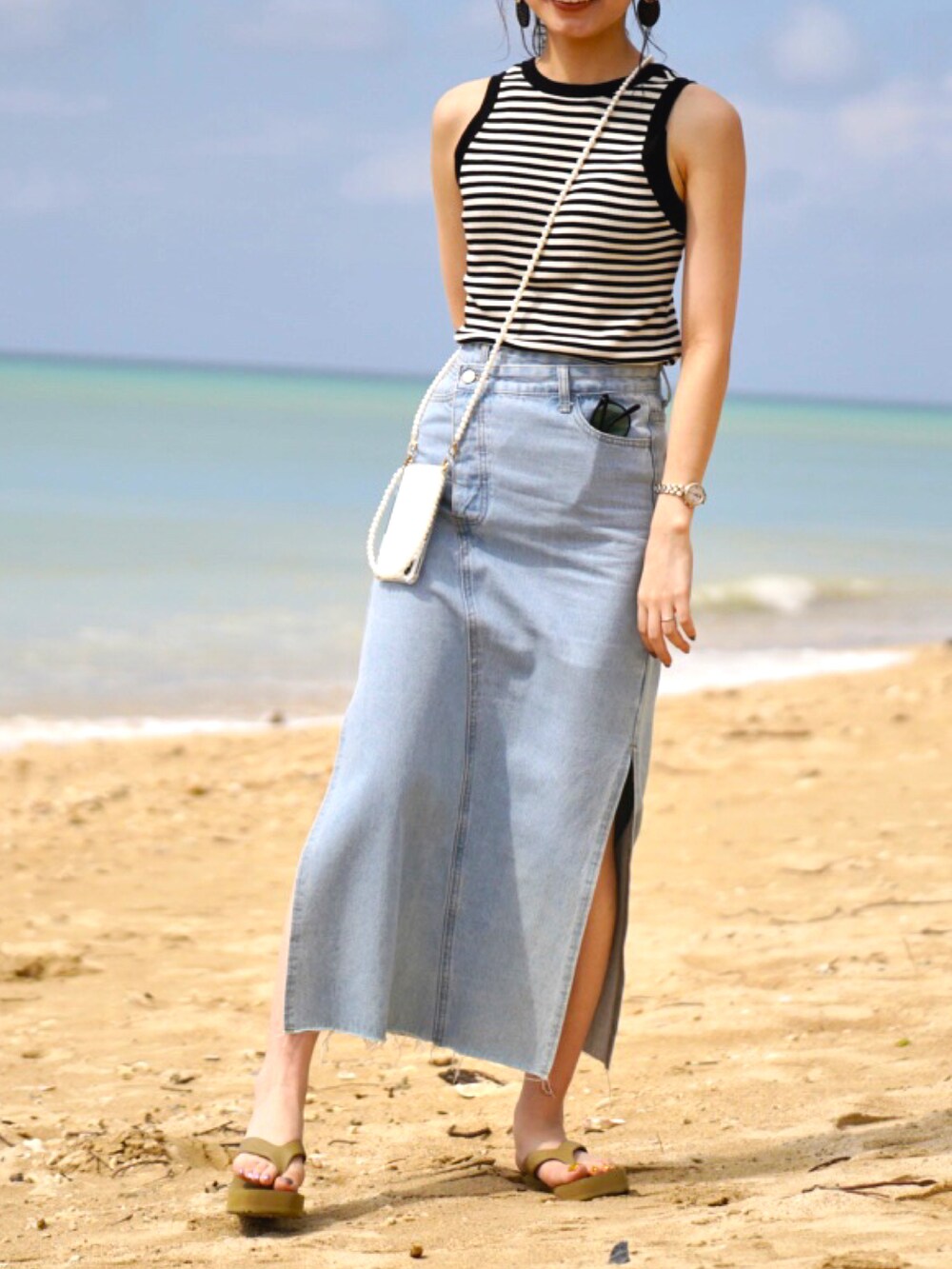 ブルー系のデニムスカート、グリーン系のサンダル、その他のタンクトップを着用したレディースの夏コーディネートの2枚目の写真
