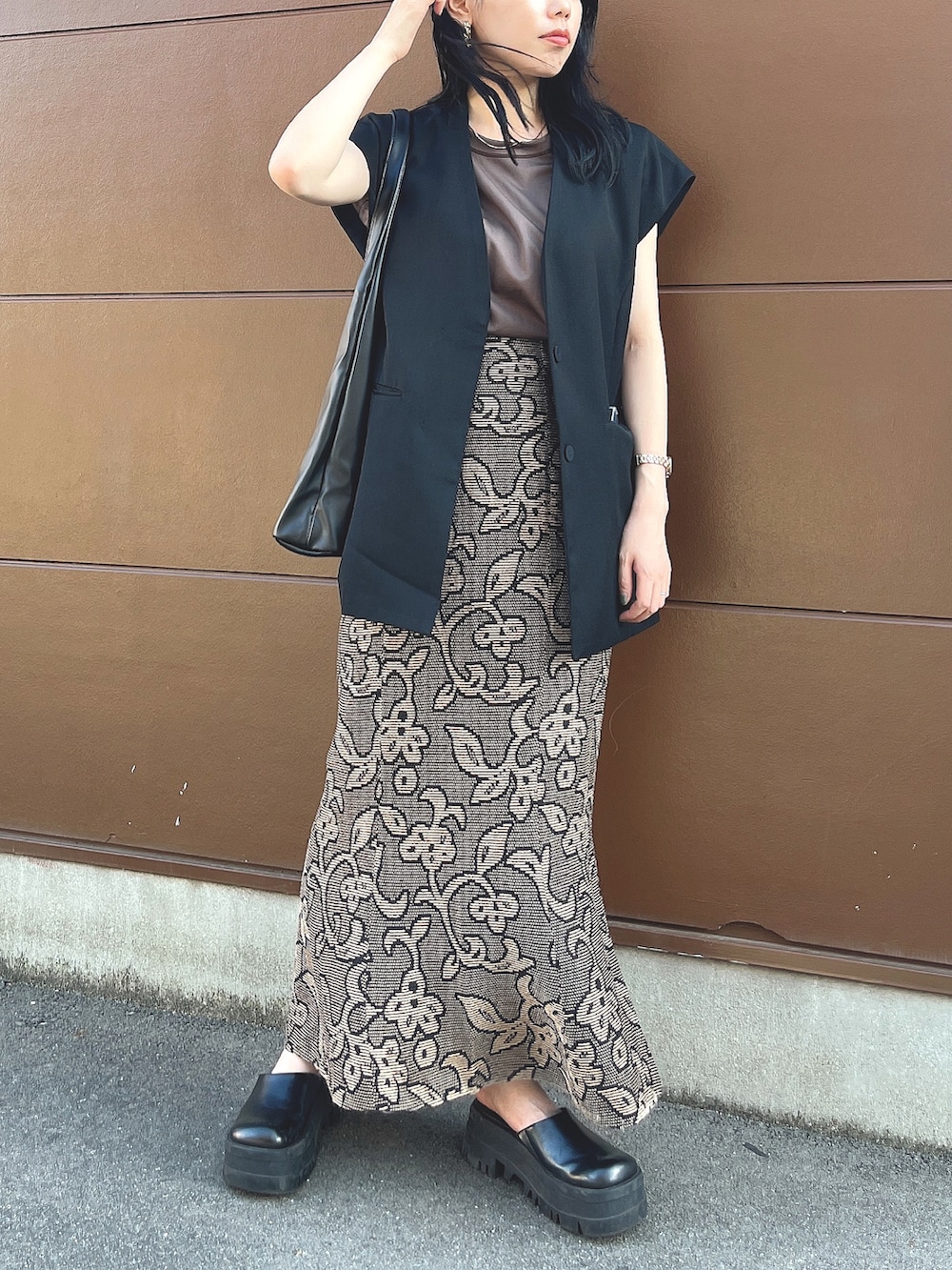 ブラック系のサンダル、ブラック系のスカート、ブラック系のベストを着用したレディースの秋コーディネートの2枚目の写真