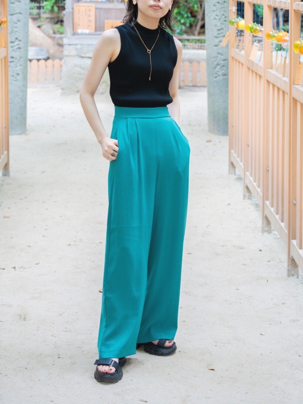 ブラック系のニット/セーター、ブラック系のサンダル、グリーン系のスラックスを着用したレディースの夏コーディネートの2枚目の写真