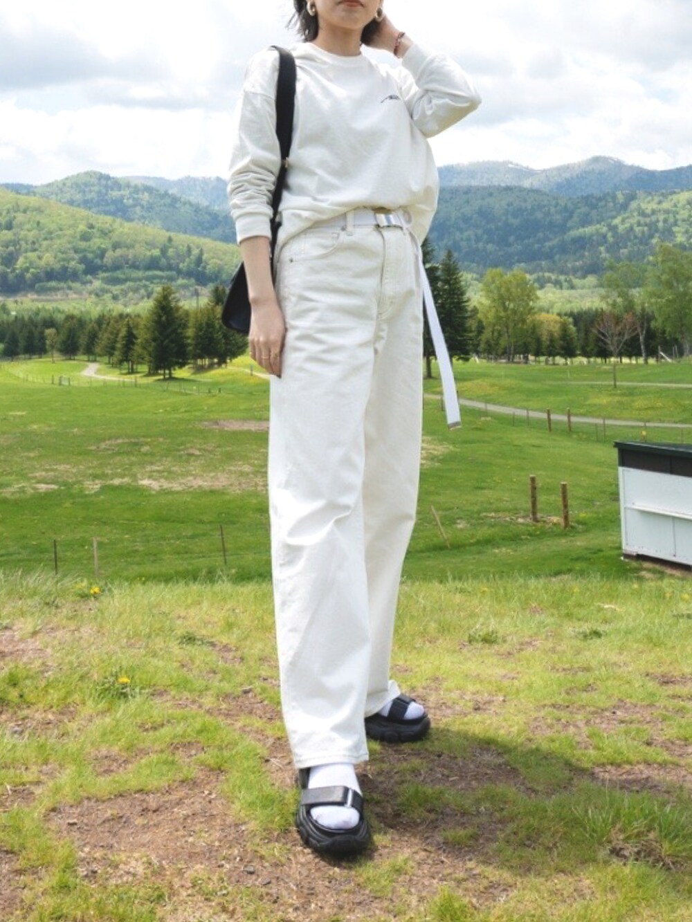 ホワイト系のデニムパンツ、ホワイト系のTシャツ/カットソー、ブラック系のサンダルを着用したレディースの夏コーディネートの3枚目の写真