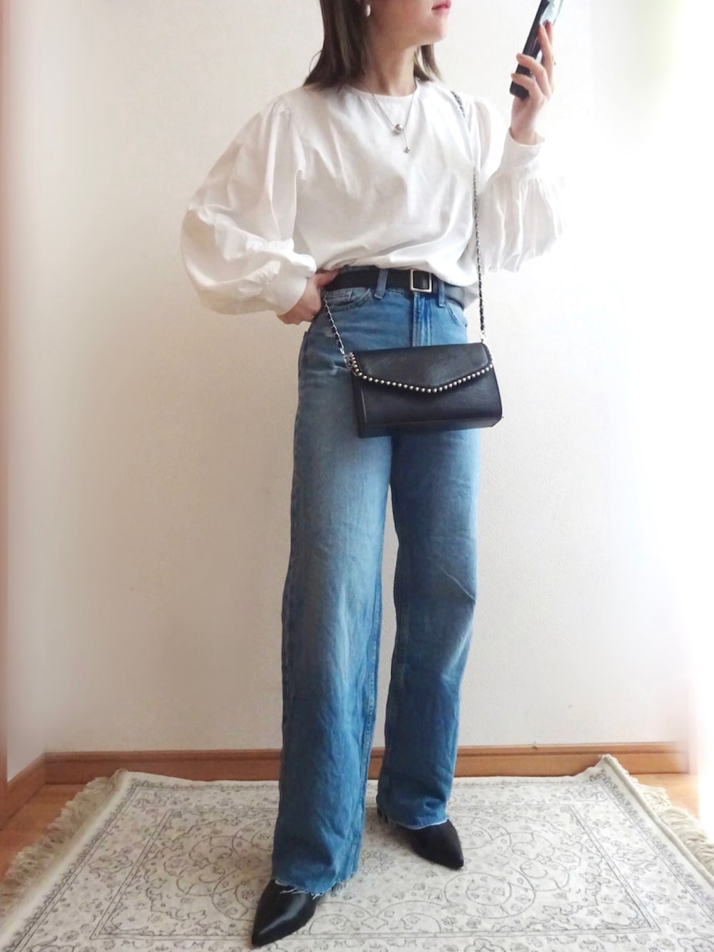 ブラック系のショルダーバッグ、グレー系のチェスターコート、ブルー系のデニムパンツを着用したレディースの冬コーディネートの2枚目の写真