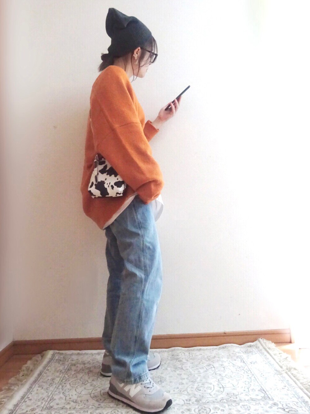 オレンジ系のニット/セーター、ブルー系のデニムパンツ、グレー系のスニーカーを着用したレディースの秋コーディネートの2枚目の写真