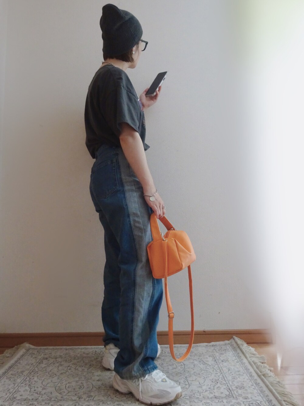 ブルー系のデニムパンツ、オレンジ系のショルダーバッグ、ホワイト系のスニーカーを着用したレディースの春コーディネートの2枚目の写真