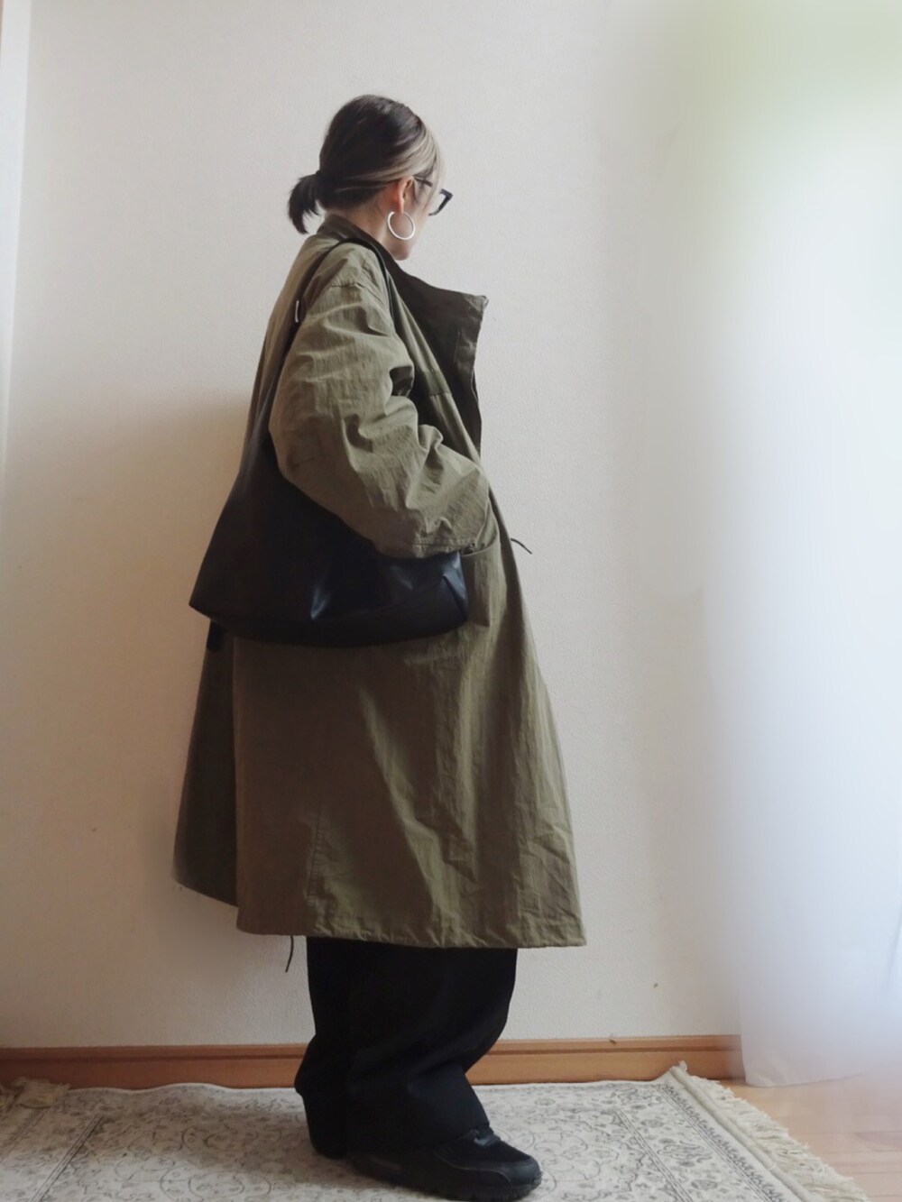 グリーン系のモッズコート、ブラック系のスニーカー、ブラック系のスラックスを着用したレディースの冬コーディネートの2枚目の写真