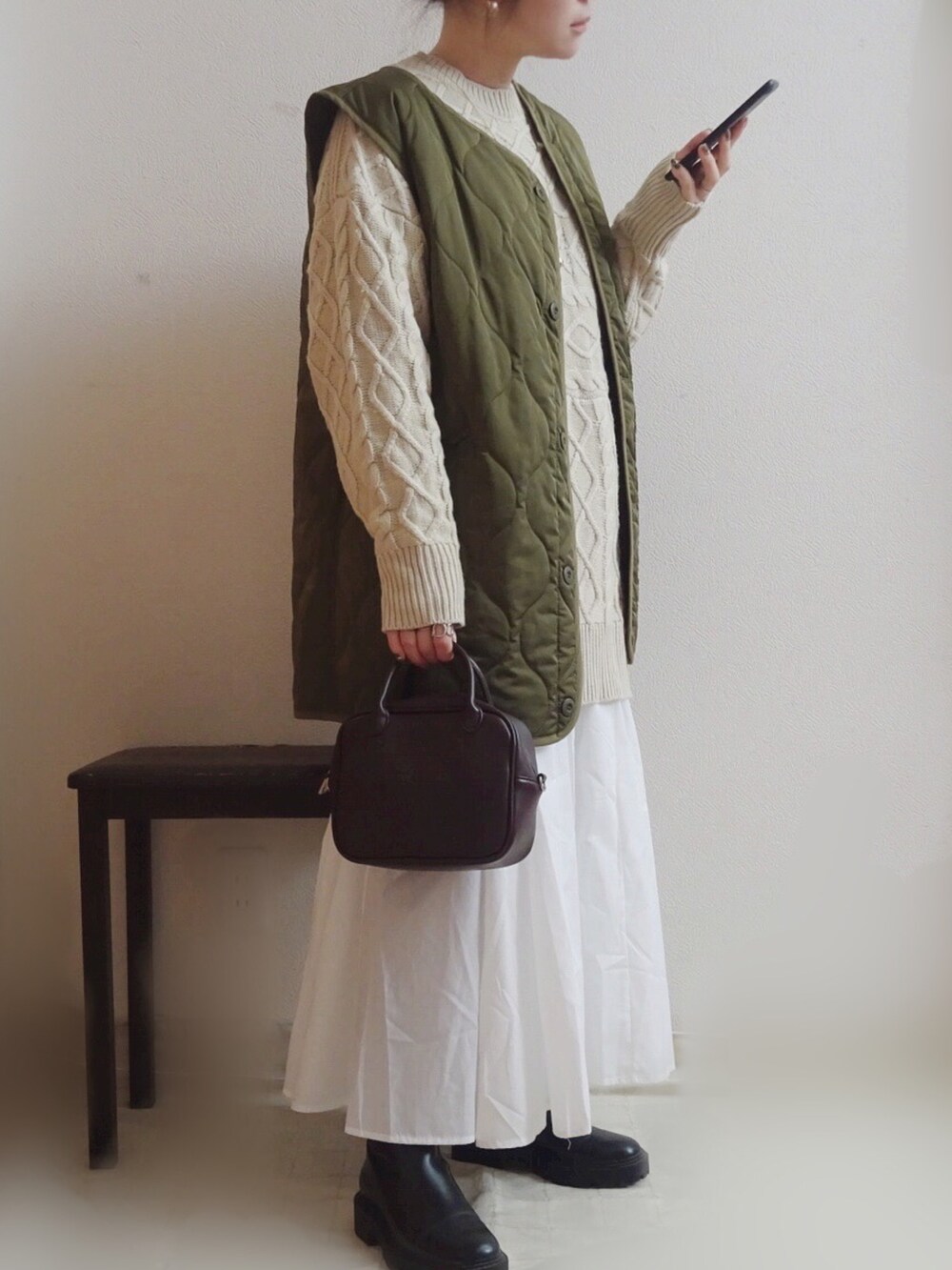 グリーン系のベスト、ホワイト系のニット/セーター、ブラウン系のボストンバッグを着用したレディースの冬コーディネートの3枚目の写真