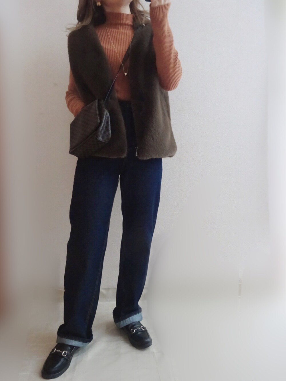 ブルー系のデニムパンツ、ブラウン系のボストンバッグ、ブラウン系のニット/セーターを着用したレディースの冬コーディネートの2枚目の写真