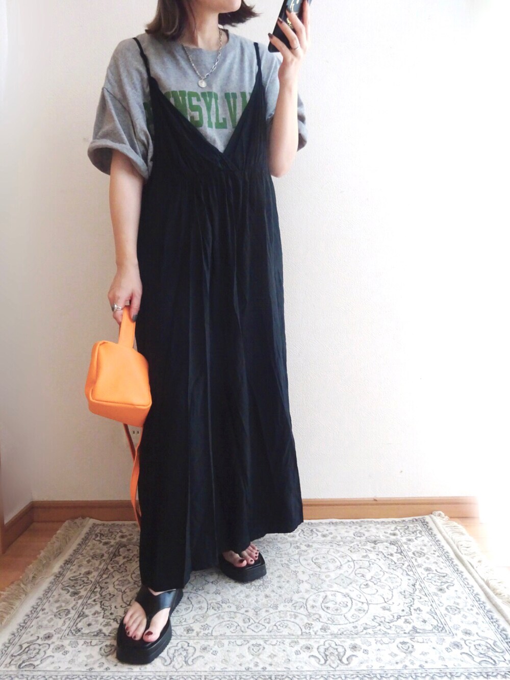 オレンジ系のショルダーバッグ、ブラック系のワンピース、グレー系のTシャツ/カットソーを着用したレディースの夏コーディネートの2枚目の写真