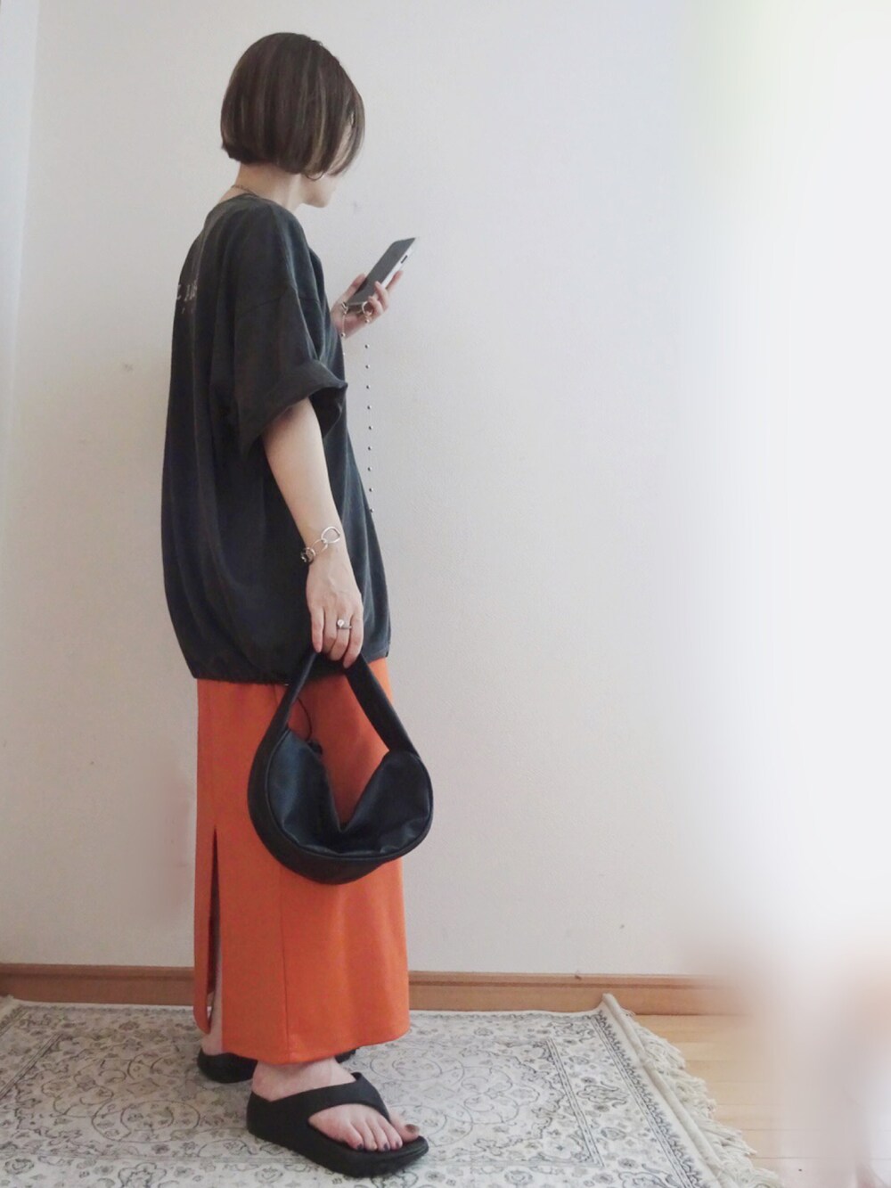 グレー系のTシャツ/カットソー、オレンジ系のスカート、ブラック系のショルダーバッグを着用したレディースの夏コーディネートの2枚目の写真