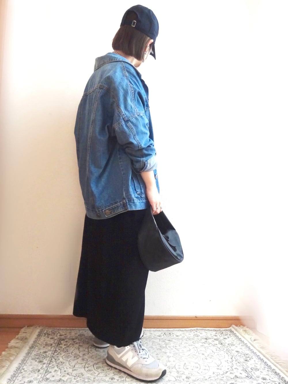 ブルー系のデニムジャケット、ブラック系のワンピース、グレー系のスニーカーを着用したレディースの春コーディネートの2枚目の写真