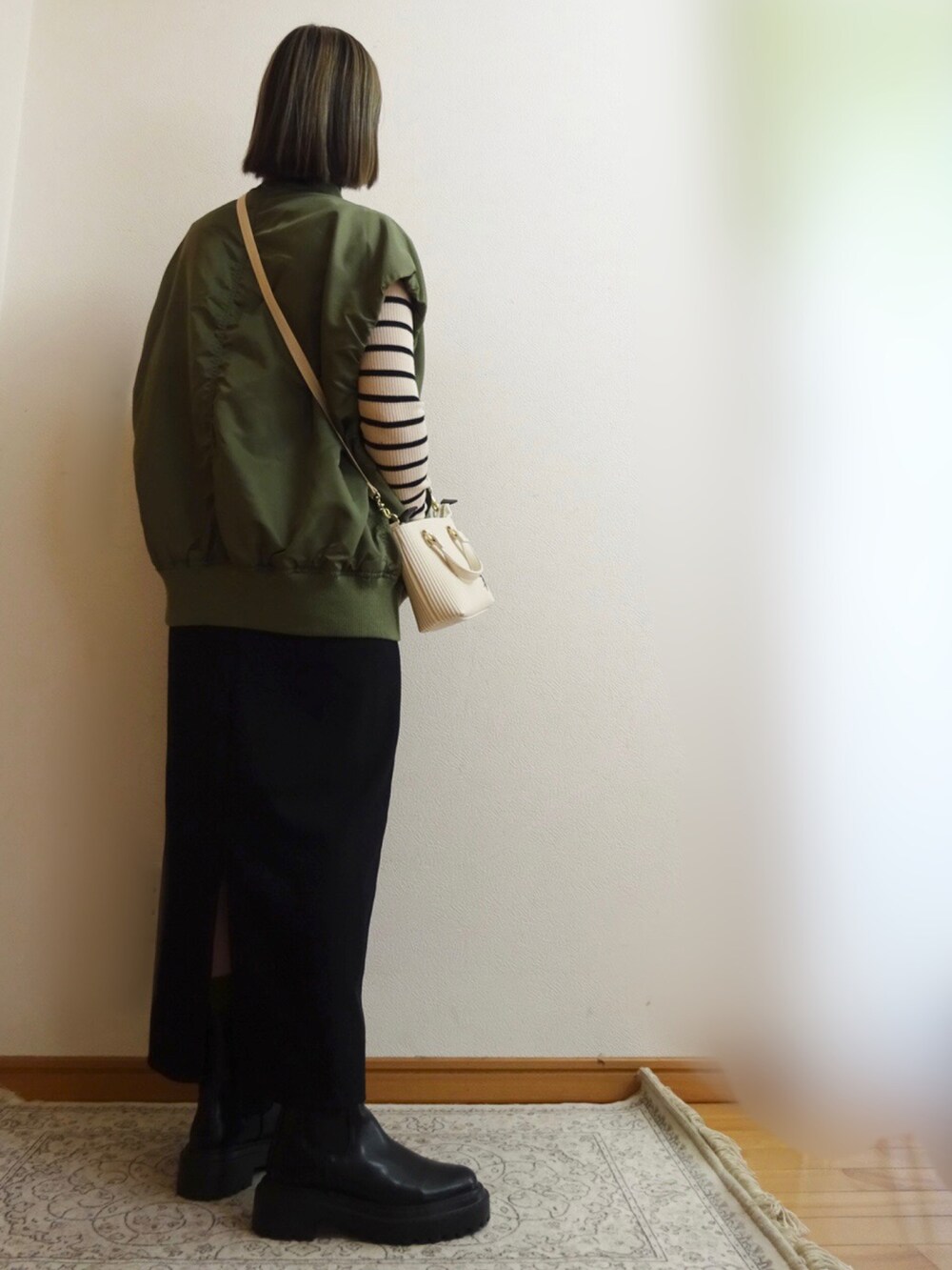 ブラック系のワンピース、グリーン系のMA-1、ホワイト系のショルダーバッグを着用したレディースの秋コーディネートの2枚目の写真