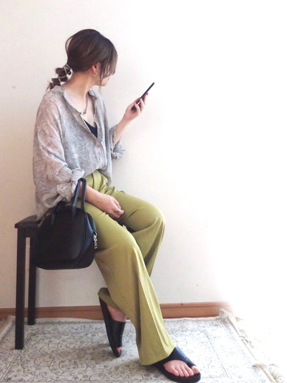 グリーン系のスラックス、ブラック系のキャミソール、ブラック系のトートバッグを着用したレディースの夏コーディネートの2枚目の写真