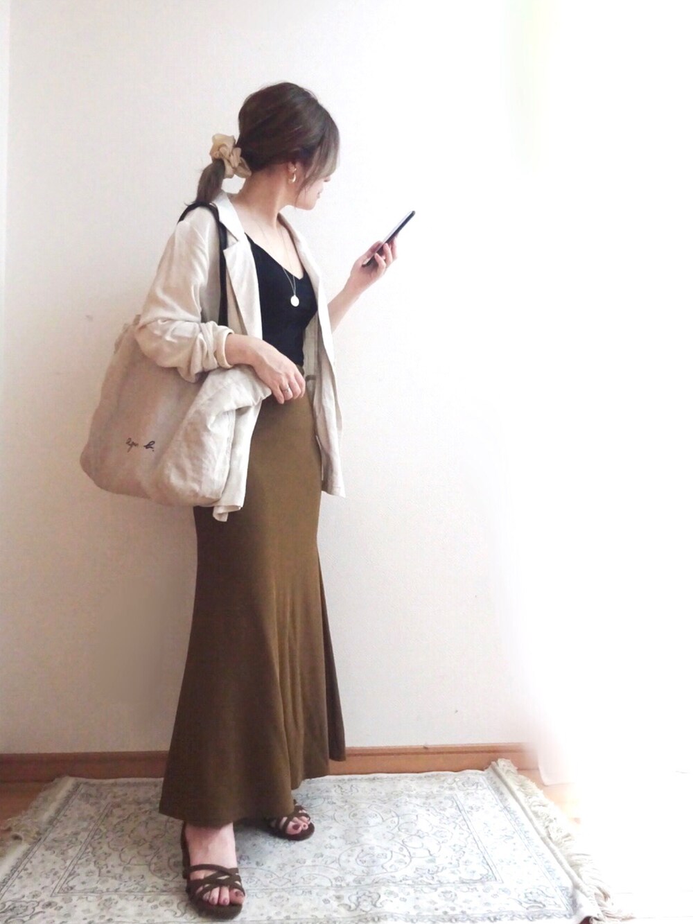 ブラック系のキャミソール、ブラック系のトートバッグ、ブラウン系のスカートを着用したレディースの夏コーディネートの2枚目の写真