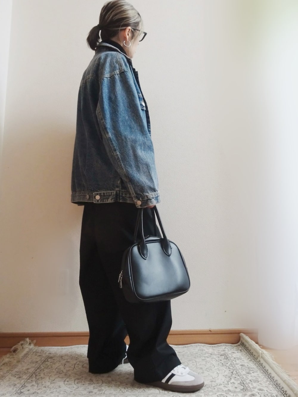 ブルー系のデニムジャケット、ブラック系のチノパンツ、ブラック系のニット/セーターを着用したレディースの冬コーディネートの2枚目の写真