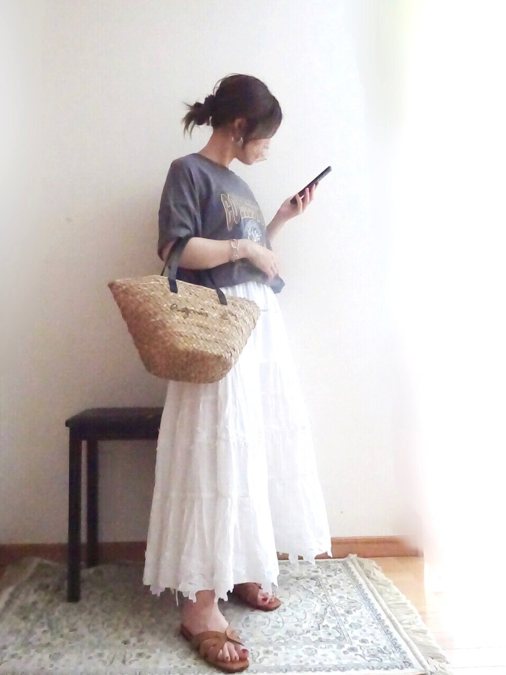 ブラック系のかごバッグ、ホワイト系のスカート、ブラウン系のサンダルを着用したレディースの夏コーディネートの2枚目の写真