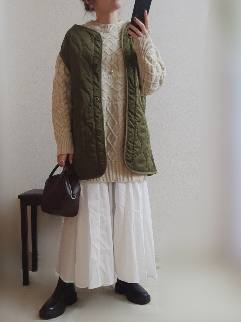 グリーン系のベスト、ホワイト系のニット/セーター、ブラウン系のボストンバッグを着用したレディースの冬コーディネートの2枚目の写真