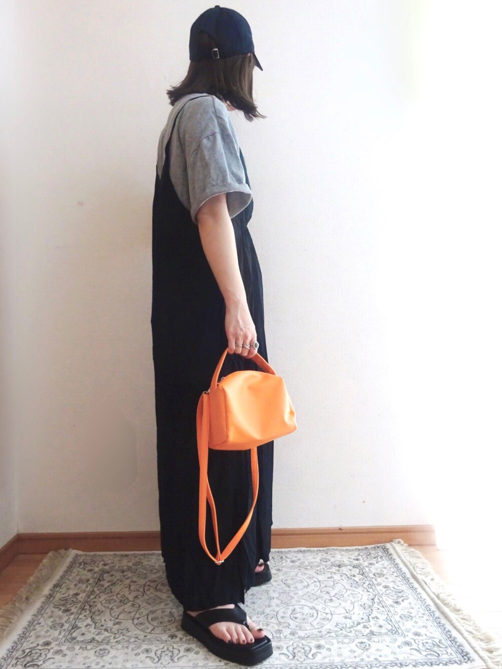 オレンジ系のショルダーバッグ、ブラック系のワンピース、グレー系のTシャツ/カットソーを着用したレディースの夏コーディネートの3枚目の写真