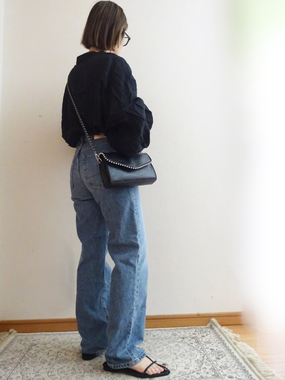 ブルー系のデニムパンツ、ブラック系のシャツ/ブラウス、ブラック系のショルダーバッグを着用したレディースの春コーディネートの2枚目の写真