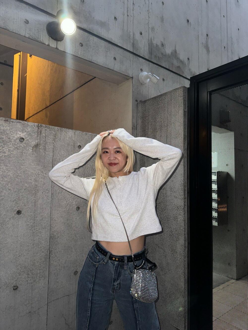 ベージュ系のTシャツ/カットソー、シルバー系のショルダーバッグ、ブルー系のデニムパンツを着用したレディースの冬コーディネートの2枚目の写真