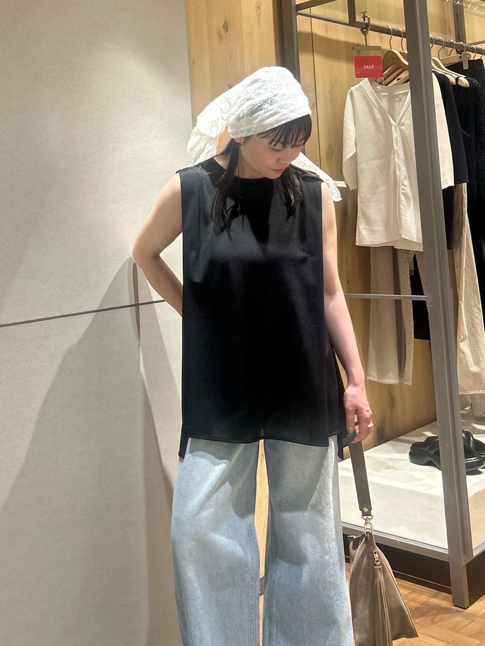 ブルー系のデニムパンツ、ブラック系のその他シューズ、ベージュ系のハンドバッグを着用したレディースの夏コーディネートの3枚目の写真