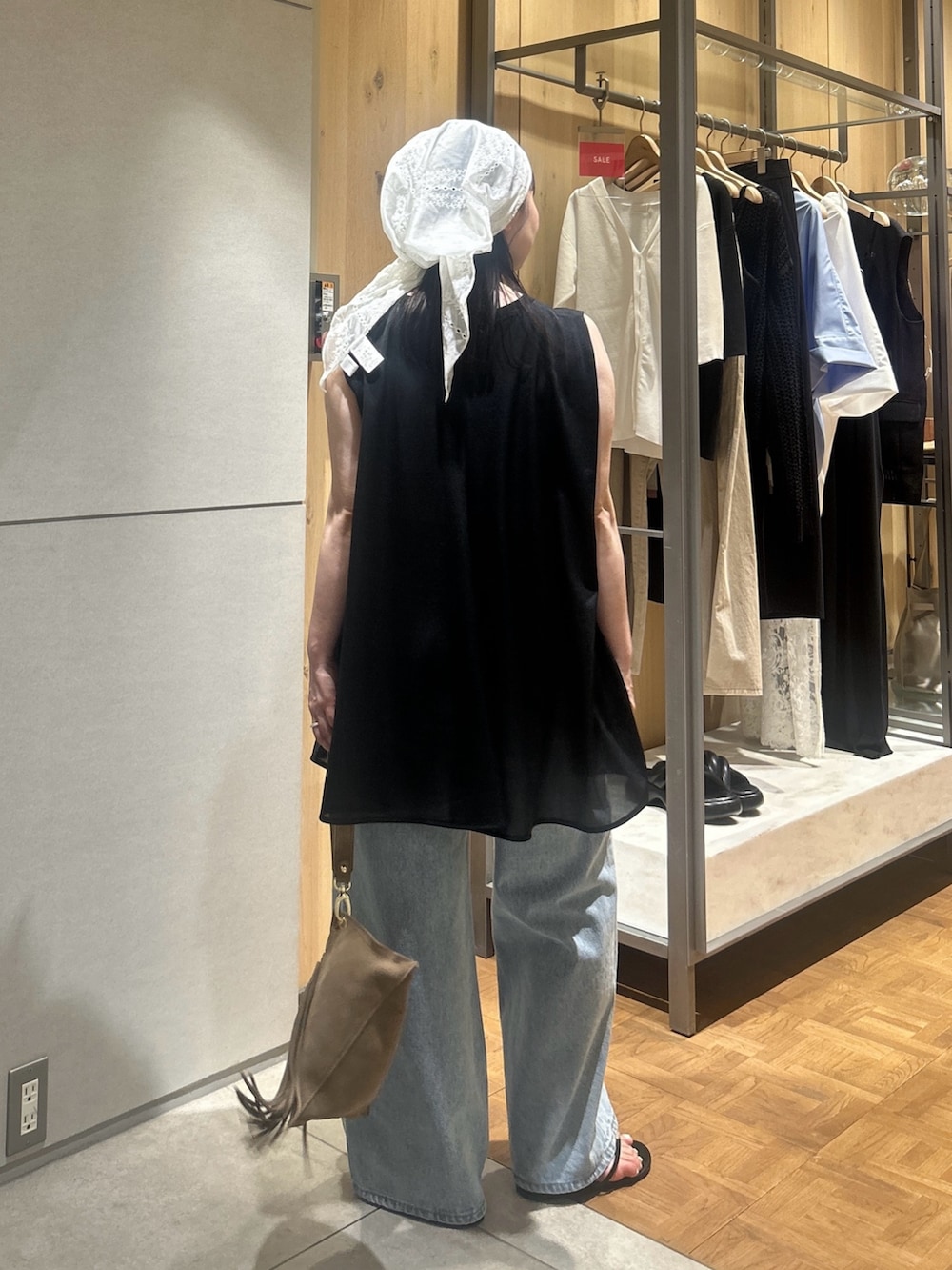 ブルー系のデニムパンツ、ブラック系のその他シューズ、ベージュ系のハンドバッグを着用したレディースの夏コーディネートの2枚目の写真