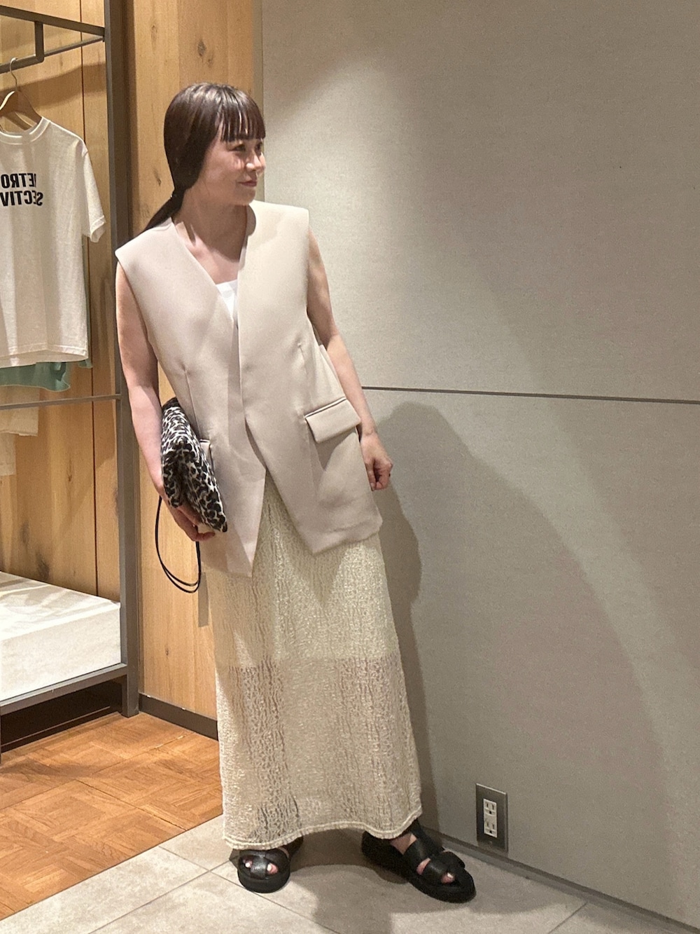 ベージュ系のベスト、ホワイト系のスカート、ブラック系のサンダルを着用したレディースの春コーディネートの2枚目の写真