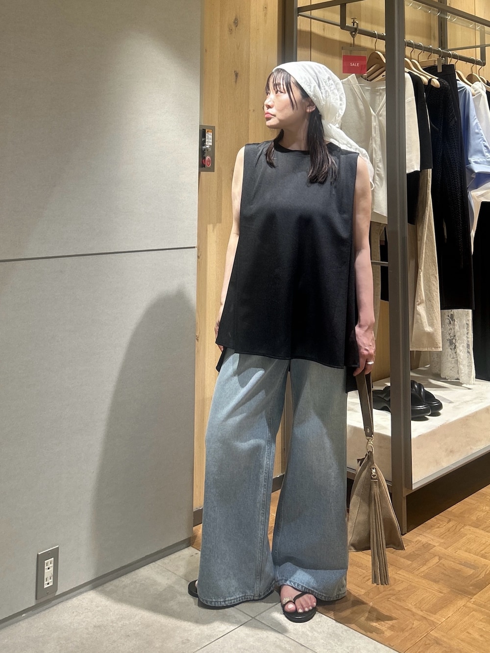 ブルー系のデニムパンツ、ブラック系のその他シューズ、ベージュ系のハンドバッグを着用したレディースの夏コーディネートの4枚目の写真