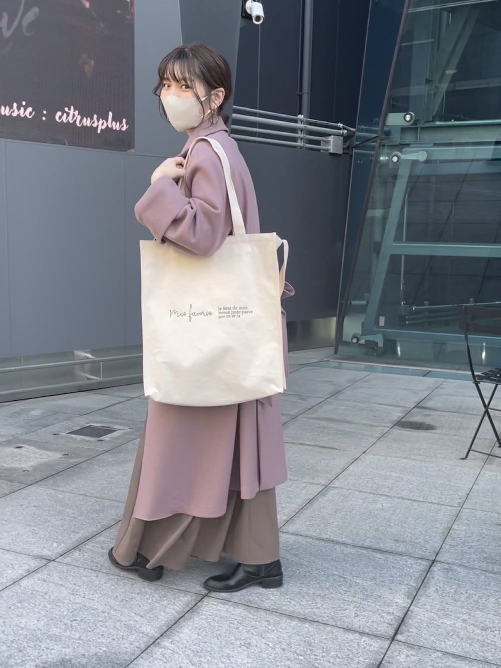 ピンク系のチェスターコート、ブラウン系のワンピースを着用したレディースの秋コーディネートの2枚目の写真