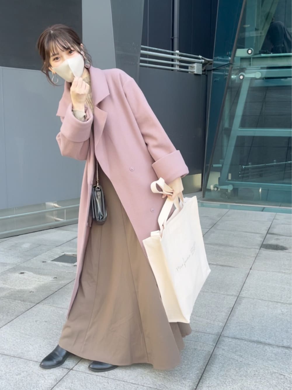 ピンク系のチェスターコート、ブラウン系のワンピースを着用したレディースの秋コーディネートの4枚目の写真
