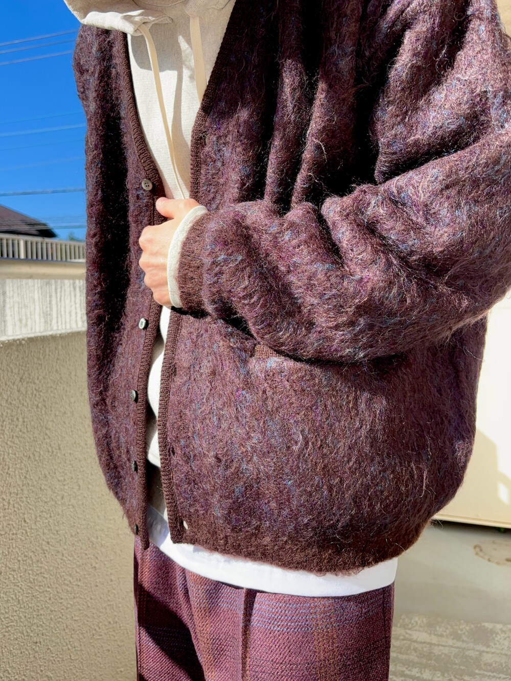 パープル系のスラックス、ブラウン系のカーディガン/ボレロ、ホワイト系のパーカーを着用したメンズの冬コーディネートの3枚目の写真