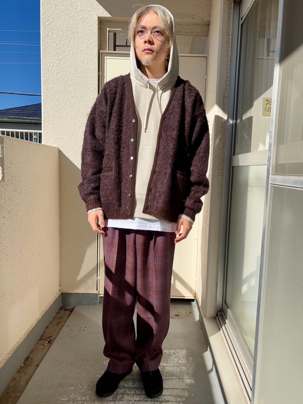 パープル系のスラックス、ブラウン系のカーディガン/ボレロ、ホワイト系のパーカーを着用したメンズの冬コーディネートの2枚目の写真