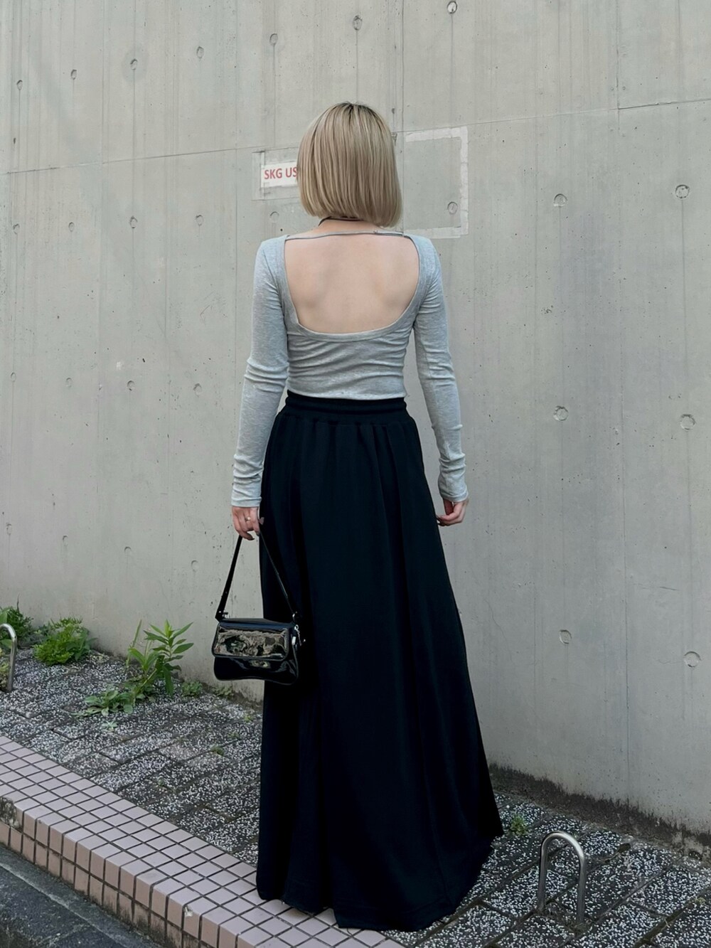 グレー系のTシャツ/カットソー、ブラック系のスカート、ブラック系のブーツを着用したレディースの秋コーディネートの2枚目の写真