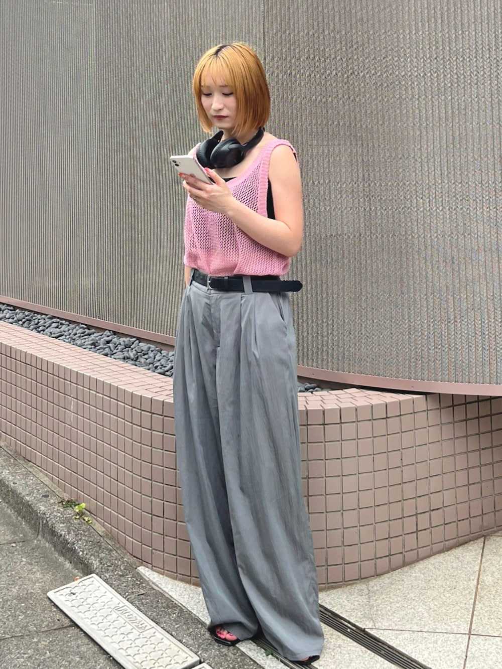 グレー系のスラックス、ピンク系のタンクトップ、ブラック系のサンダルを着用したレディースの夏コーディネートの2枚目の写真