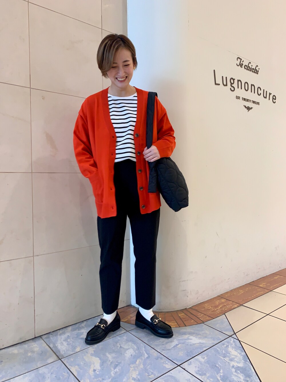 ホワイト系のTシャツ/カットソー、レッド系のカーディガン/ボレロ、ブラック系のハンドバッグを着用したレディースの秋コーディネートの2枚目の写真