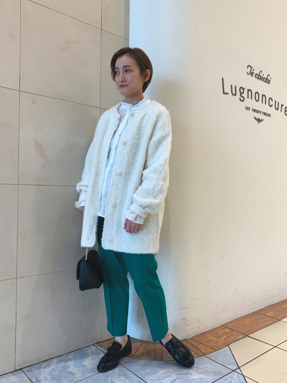 ホワイト系のシャツ/ブラウス、ホワイト系のカーディガン/ボレロ、ブラック系のハンドバッグを着用したレディースの冬コーディネートの2枚目の写真