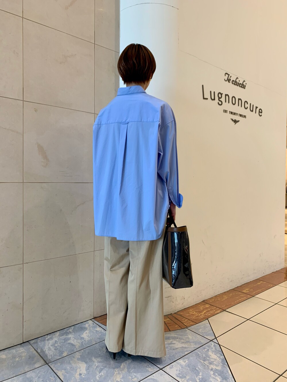 ブルー系のシャツ/ブラウス、ベージュ系のチノパンツ、ブルー系のハンドバッグを着用したレディースの春コーディネートの3枚目の写真