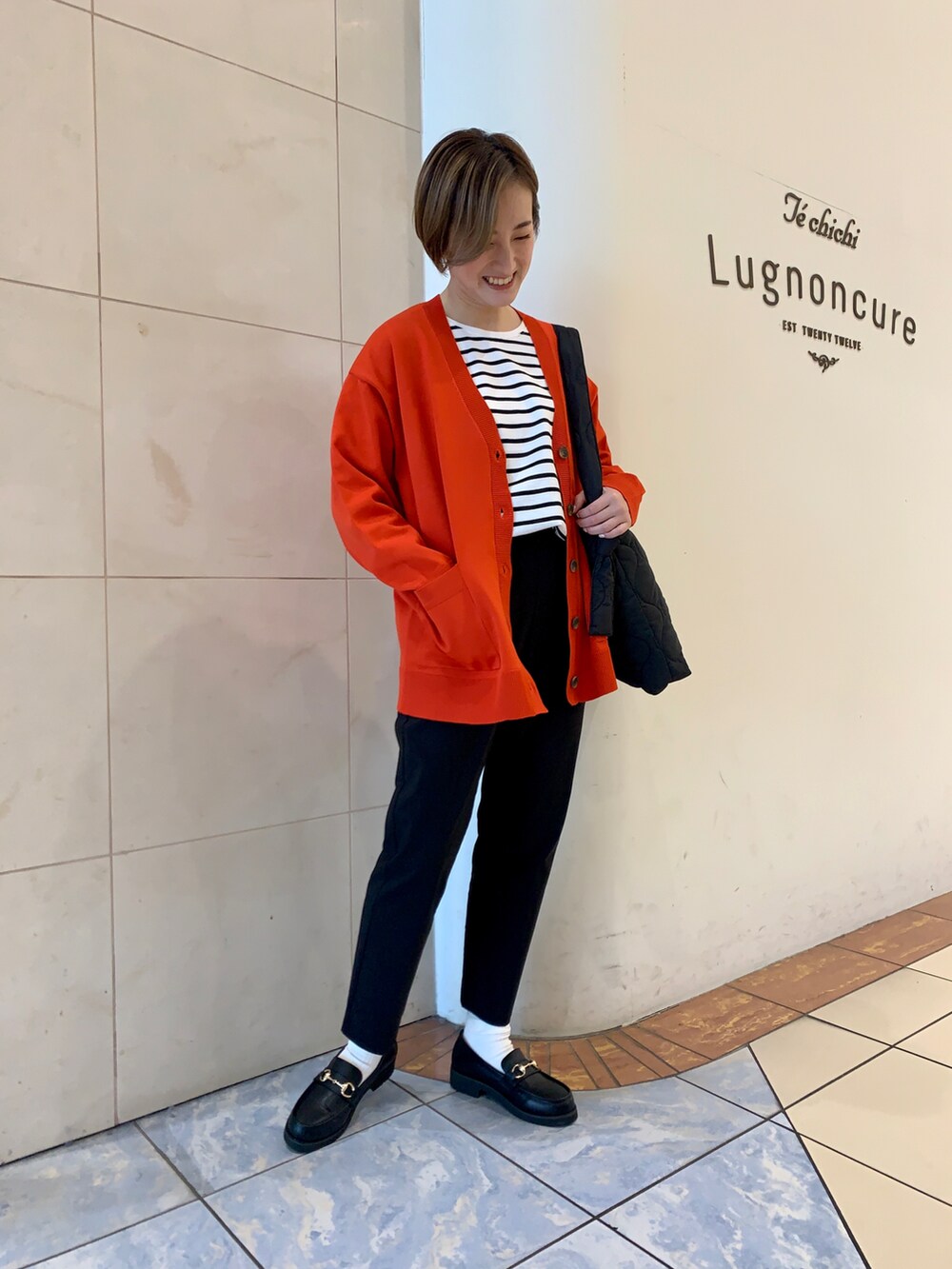 ホワイト系のTシャツ/カットソー、レッド系のカーディガン/ボレロ、ブラック系のハンドバッグを着用したレディースの秋コーディネートの3枚目の写真