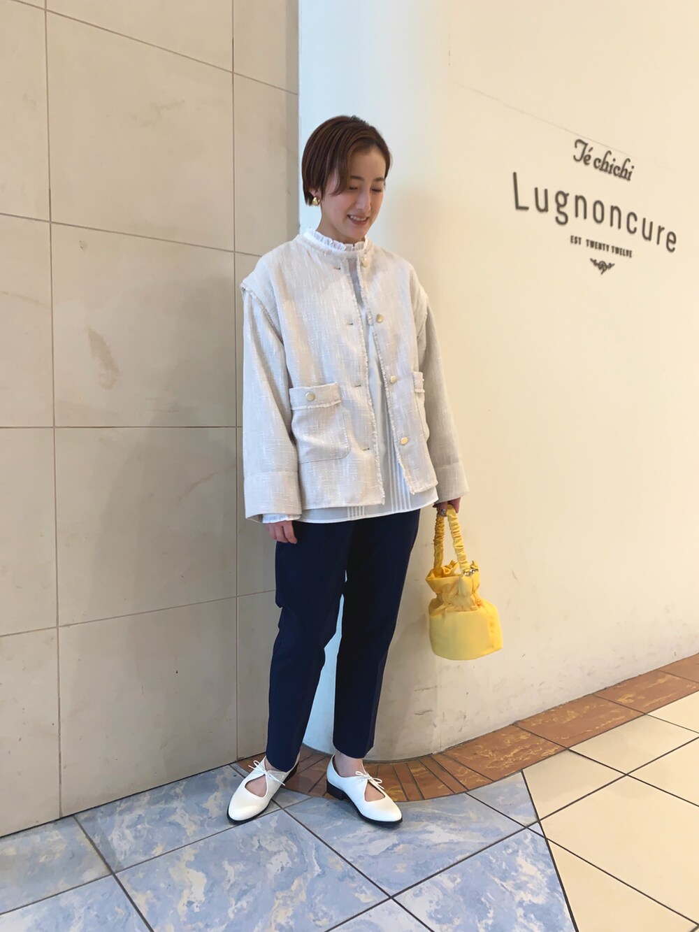ホワイト系のノーカラージャケット、ホワイト系のシャツ/ブラウス、イエロー系のハンドバッグを着用したレディースの春コーディネートの3枚目の写真