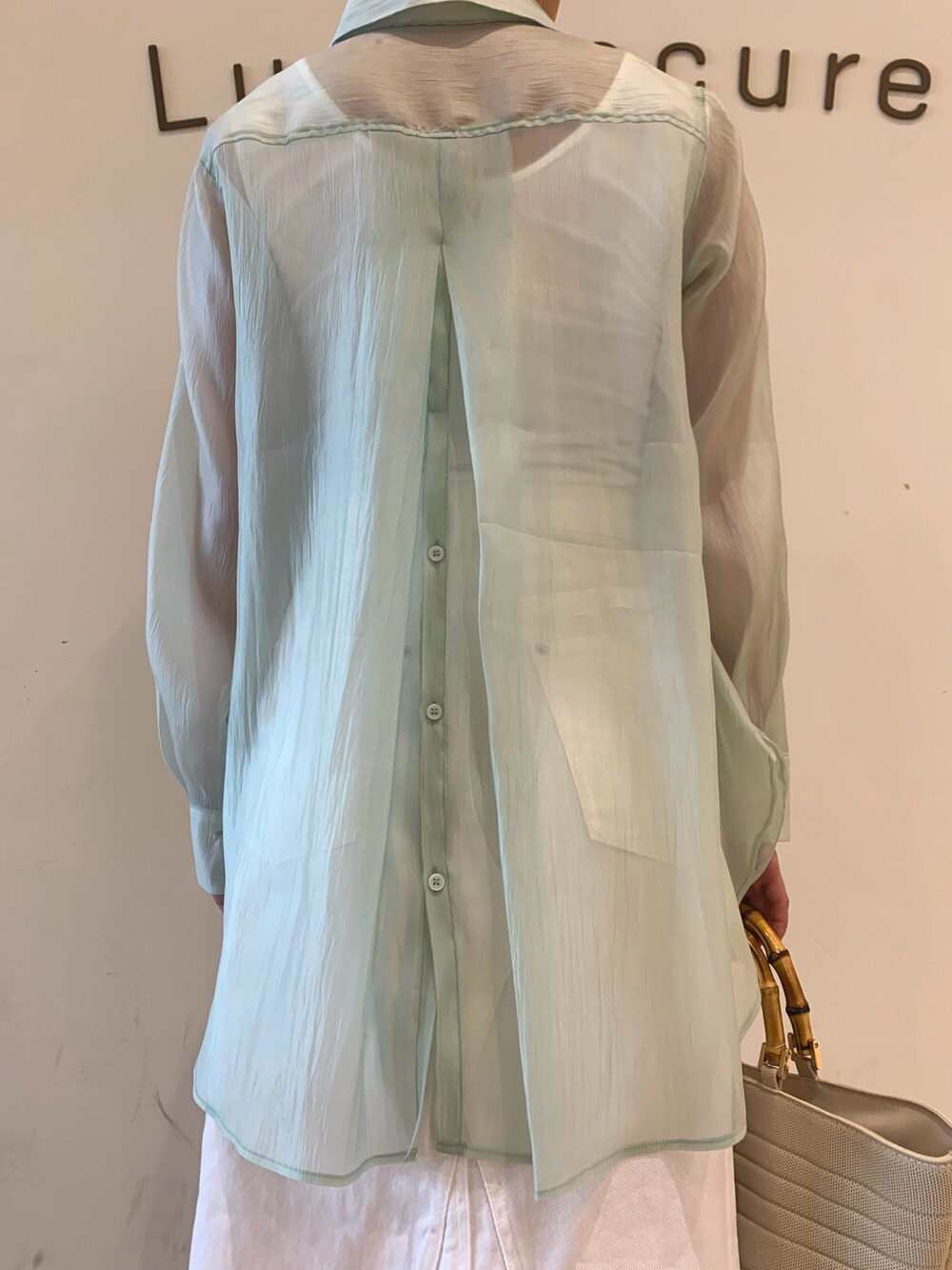 グリーン系のシャツ/ブラウス、ホワイト系のスカート、ホワイト系のパンプスを着用したレディースの春コーディネートの4枚目の写真