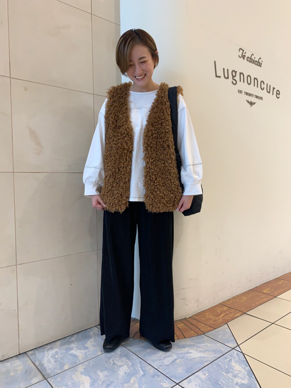 ホワイト系のTシャツ/カットソー、イエロー系のベスト、ブラック系のハンドバッグを着用したレディースの秋コーディネートの2枚目の写真