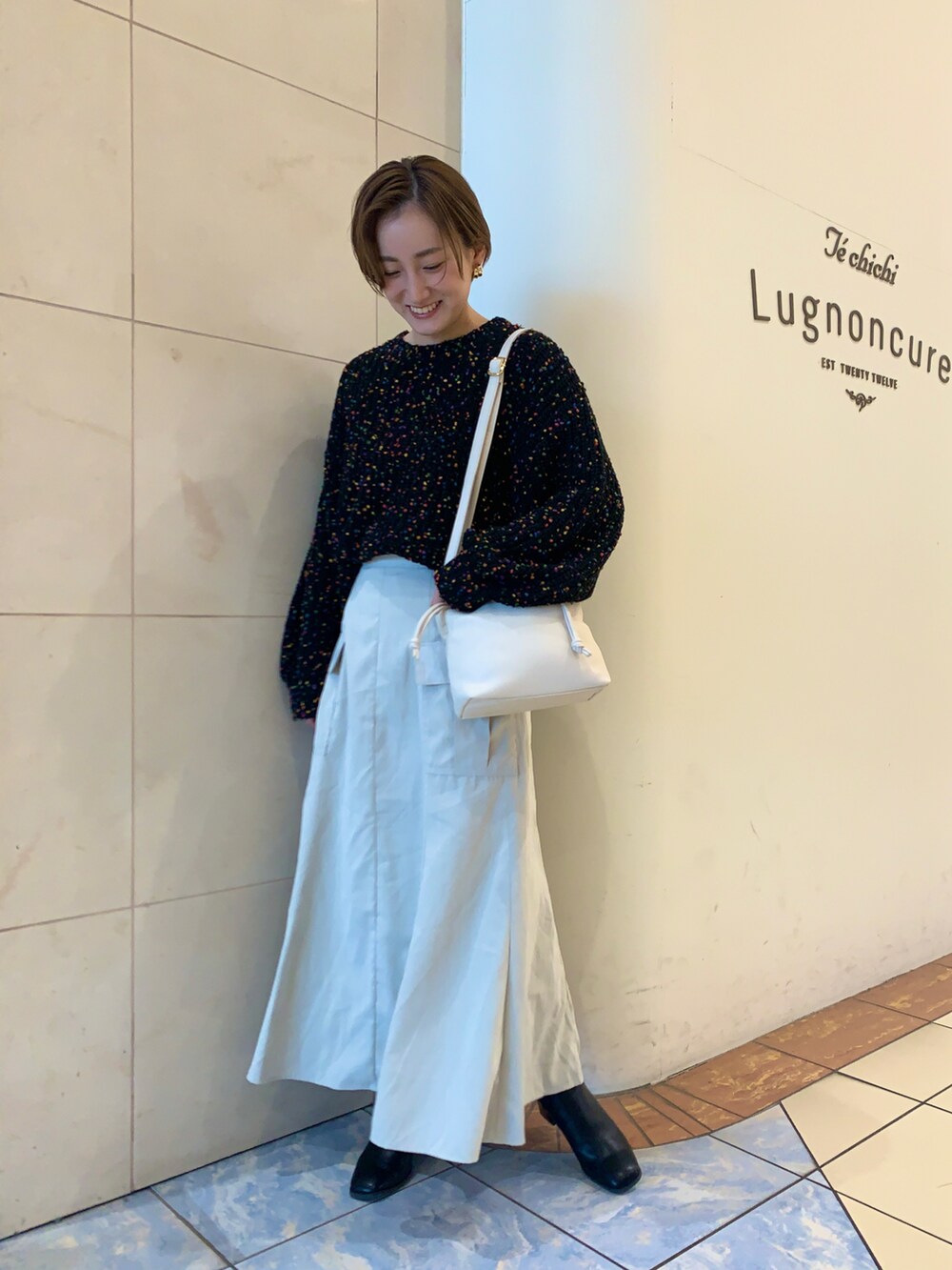 ブラック系のニット/セーター、ホワイト系のスカート、ブラック系のブーツを着用したレディースの冬コーディネートの3枚目の写真