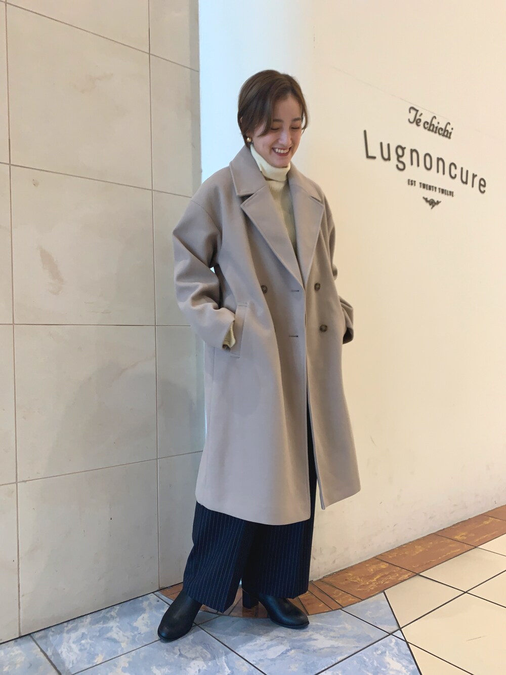 ブラウン系のチェスターコート、ブルー系のその他パンツ、ブラック系のブーツを着用したレディースの冬コーディネートの2枚目の写真